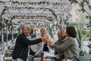 Cheerful male and female senior friends toasting drinks at restaurant - MASF39805