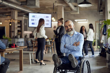 Portrait of happy bearded businessman with disability on wheelchair at office - MASF39866