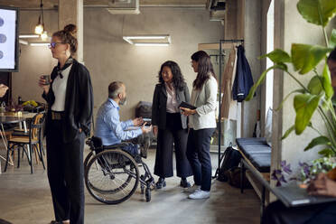 Female colleagues discussing with disabled businessman at creative office - MASF39869