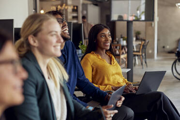 Happy multiracial business professionals sitting together at office - MASF39878