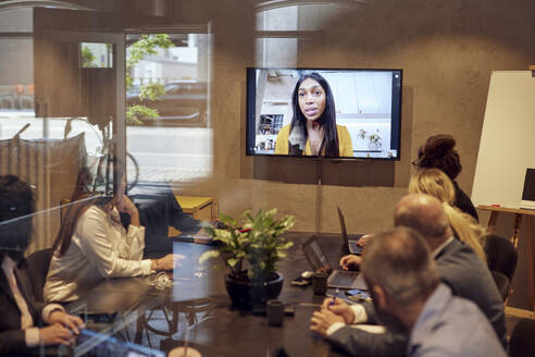 Geschäftsfrau bespricht sich per Videokonferenz mit Kollegen im Büro - MASF39885