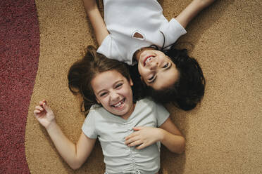 Directly above view of happy sisters lying on footpath - MASF39899