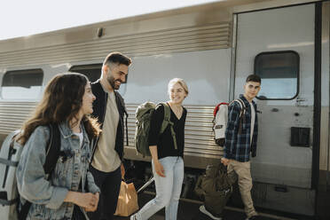 Glückliche Familie mit Gepäck zu Fuß in der Nähe von Zug am Bahnhof - MASF39934