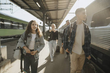 Familie auf dem Weg in den Urlaub bei einem Spaziergang am Bahnhof an einem sonnigen Tag - MASF39938