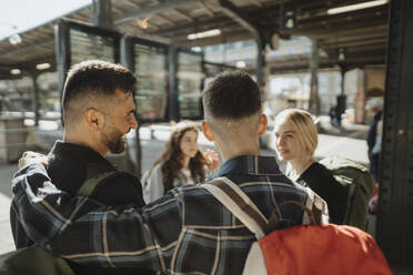 Rückansicht eines Jungen, der seinen Vater in den Arm nimmt und am Bahnhof wartet - MASF39952