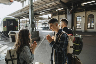 Bruder spielt Freizeitspiel mit Schwester beim Warten auf Zug am Bahnhof - MASF39961