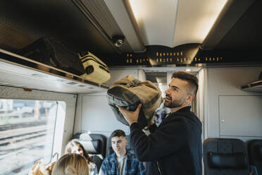 Mann lädt das Gepäck der Familie auf ein Regal im Zug - MASF39969