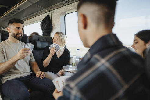 Family enjoying and having fun while playing cards in train - MASF39983