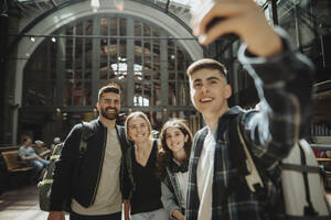 Fröhliche Familie, die zusammen ein Selfie macht, während sie am Bahnhof steht - MASF40013