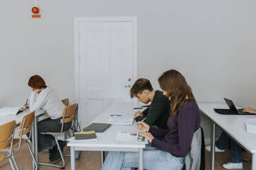 Seitenansicht von Schülern, die an Schreibtischen im Klassenzimmer lernen - MASF40043