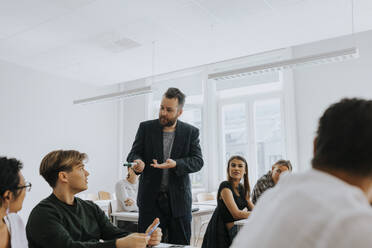 Professor unterrichtet, während er mit einem männlichen Studenten im Klassenzimmer spricht - MASF40067