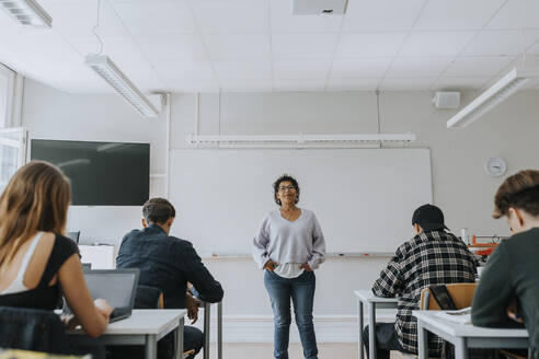 Porträt einer Lehrerin mit Schülern vor einer Tafel im Klassenzimmer - MASF40071