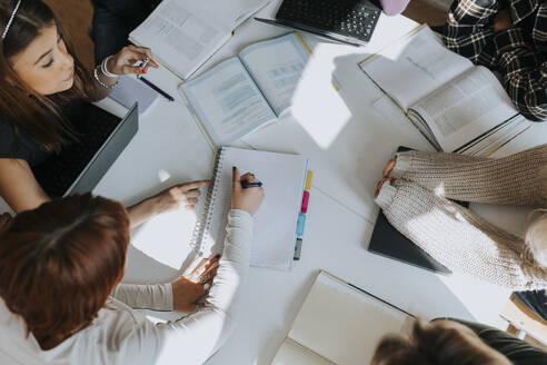 High angle view of students studying together at desk in classroom - MASF40076