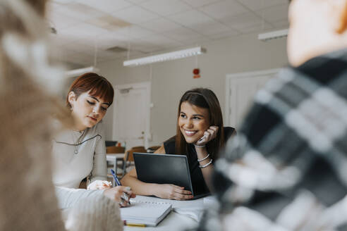 Smiling teenage student sitting by friend studying in classroom - MASF40078