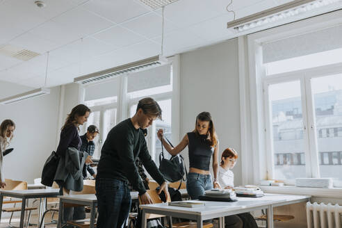 Male and female students by desks in classroom - MASF40094