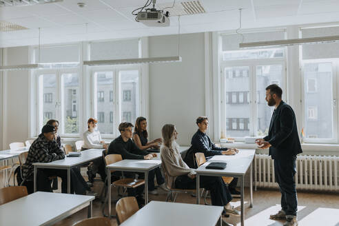 Professor teaching multiracial students sitting in classroom - MASF40096