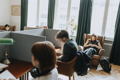 Teenager sitzt in der Nähe von Studentinnen in der Bibliothek - MASF40104