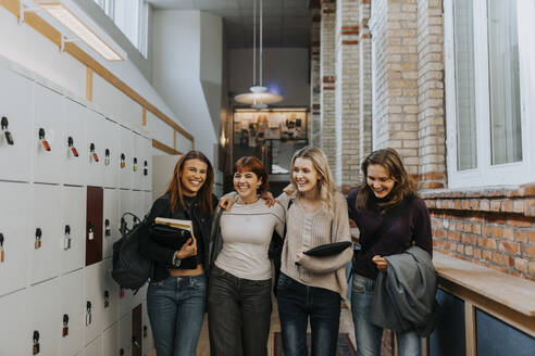 Happy female students walking in school corridor - MASF40128