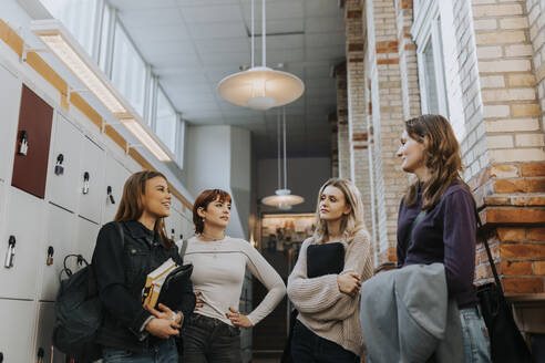 Female students talking while standing in school corridor - MASF40129