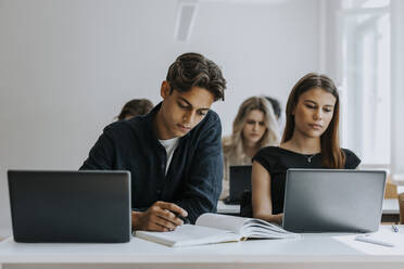 Männliche und weibliche Teenager verschiedener Rassen lernen am Schreibtisch im Klassenzimmer - MASF40142