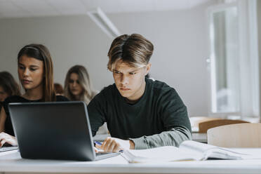 Teenager, der im Klassenzimmer auf seinen Laptop starrt - MASF40143