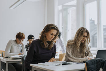 Junge Studentinnen lernen am Schreibtisch im Klassenzimmer - MASF40145