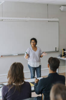 Lehrer gestikuliert beim Unterrichten von Schülern, die im Klassenzimmer sitzen - MASF40147