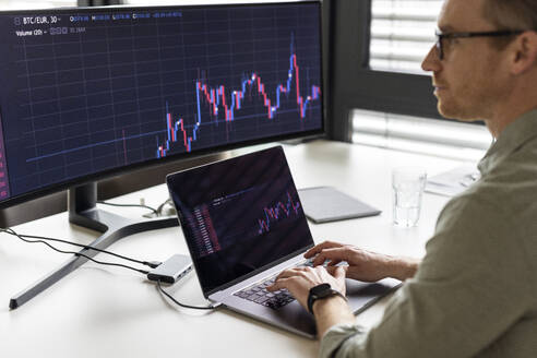 Businessman examining graph on desktop PC at desk - PESF04084