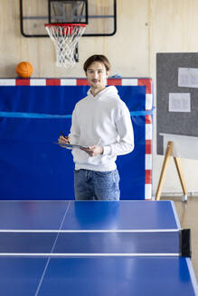 Junger Geschäftsmann stehend mit Tablet-PC in der Nähe eines Tennistisches - PESF04112