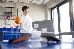 Junger Geschäftsmann spielt mit Basketball im Büro - PESF04117