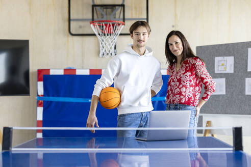 Smiling young trainee standing with businesswoman in office - PESF04123