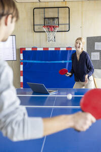 Geschäftsleute spielen Tennis in einem modernen Büro - PESF04133