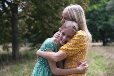 Glückliche Mutter und Tochter umarmen sich in einem öffentlichen Park - AMWF01848