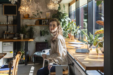 Young businesswoman sitting near table at cafe - VPIF08706