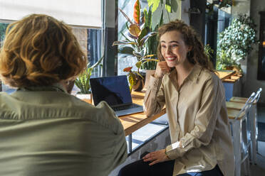 Smiling young businesswoman sitting with colleague at cafe - VPIF08709