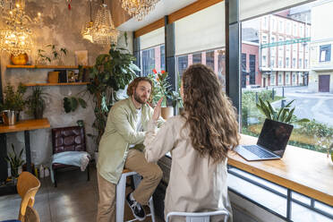 Geschäftsfrau, die mit einem Kollegen im Café sitzend eine Strategie plant - VPIF08713