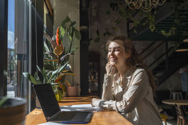 Happy young businesswoman sitting at cafe - VPIF08725