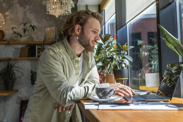 Junger Geschäftsmann arbeitet an einem Laptop in einem Café - VPIF08739