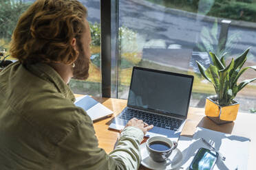 Geschäftsmann mit Laptop auf dem Tisch in einem Cafe - VPIF08740