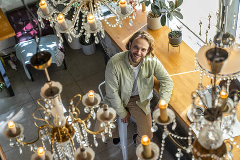 Smiling businessman looking up sitting at cafe - VPIF08742