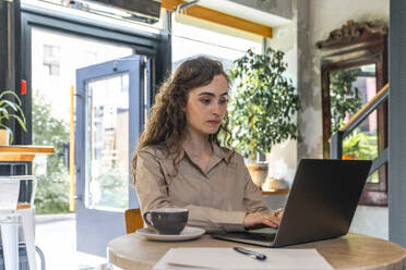 Junge Geschäftsfrau arbeitet an einem Laptop in einem Café - VPIF08756