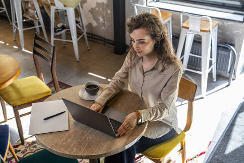 Junge Geschäftsfrau mit Laptop am Tisch in einem Café - VPIF08757