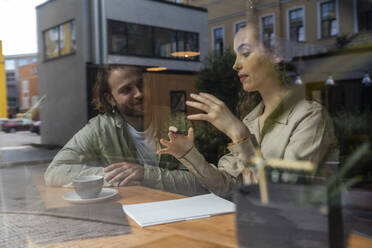 Junge Geschäftsfrau gestikuliert und erklärt einem Kollegen im Café - VPIF08772