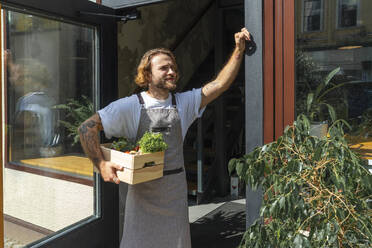 Owner with vegetable crate waiting at store entrance - VPIF08785