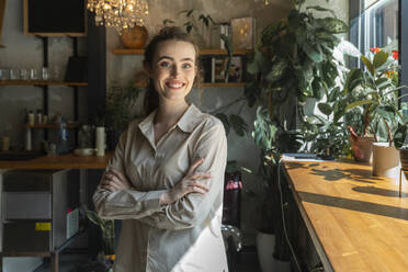 Happy businesswoman standing with arms crossed at cafe - VPIF08803