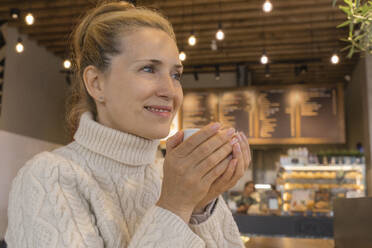 Lächelnde Geschäftsfrau mit einer Tasse Kaffee in einem Cafe - OSF02200