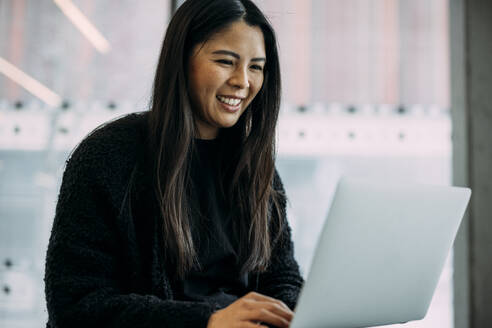Lächelnde Geschäftsfrau mit Laptop im Büro - JOSEF21348