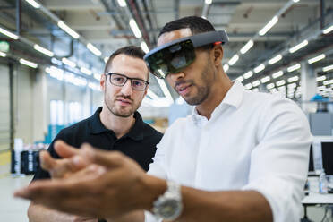 Techniker mit Augmented-Reality-Brille in einer Fabrik interagiert mit einem Kollegen - DIGF20582