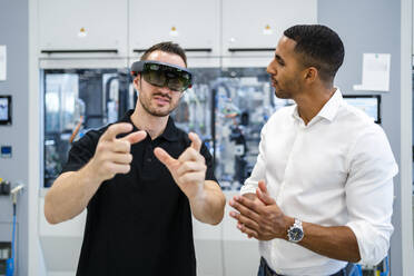 Techniker mit Augmented-Reality-Brille in einer Fabrik interagiert mit einem Kollegen - DIGF20590