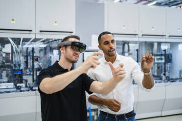 Techniker mit Augmented-Reality-Brille in einer Fabrik interagiert mit einem Kollegen - DIGF20593